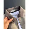 Chaqueta morada tie-dye estilo americano de alta calle 2026 con un patrón oscuro, que presenta un corte entallado, un aspecto sofisticado y una colección de primavera con cuello alto, diseñada como una chaqueta de cuero estilo ropa de trabajo para hombre