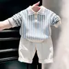 Ropa infantil coreana 2026 otoño nuevo suéter de punto con cuello polo a rayas azules conjunto de pantalones casuales blancos para niños