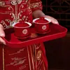Um conjunto de xícaras de chá de casamento, incluindo um par de tigelas de chá e pauzinhos vermelhos e festivos, perfeito para servir chá durante a cerimônia de casamento.