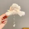 Coleção Outono/Inverno 2026: presilha de cabelo de pelúcia com design de tubarão para a parte de trás da cabeça, criando um look estiloso e retrô em uma sofisticada cor marrom, adequada para mulheres