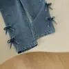 Estilo europeo y americano: un atuendo de niña dulce y delicado que presenta un top blanco, suave y de manga larga con un diseño de lazo completo en el lateral, combinado con pantalones de mezclilla - un conjunto de dos piezas