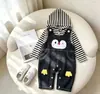 Conjunto de macacão jeans com estampa de pinguim de desenho animado para bebês e crianças pequenas, apresentando uma camada interna com capuz listrada em preto e branco e macacão jeans
