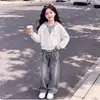 Conjunto de moda para principios de otoño para niñas: un elegante conjunto de dos piezas que presenta un top con capucha y bloques de color y unos pantalones vaqueros de diseño único
