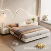 Cama matrimonial de color crema, diseño flotante, sin cabecero, con tira de iluminación LED debajo de la cama, unidad de almacenamiento de gran capacidad en el dormitorio principal y una estructura de cama cubierta de cuero.