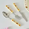 Conjunto de talheres quadrado com cabo de cerâmica em aço inoxidável 304, incluindo uma colher e um garfo na cor creme, um design fofo de urso de pão, e facas e garfos de churrasco