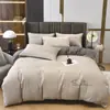 Venta al por mayor del fabricante Juego de cuatro piezas de color sólido de lujo ligero Rojo brillante Sábanas de cama bordadas para bodas Funda de edredón Algodón lavado Ropa de cama cepillada