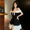 Elegante vestido de tirantes asimétricos con lazo de color contrastante, efecto reductor y que disimula el abdomen, con falda amplia