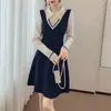 Vestido suéter de tricô com blocos de cor, gola de boneca estilo Hong Kong, combinado com um casaco e saia base.