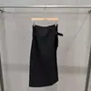 Coleção Outono/Inverno 2026 transfronteiriça: saia midi preta de cintura alta com detalhes de fivela metálica, apresentando uma fenda alta e um design simples e versátil adequado para o trabalho ou para o dia a dia