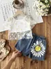 Conjunto de Tres Piezas para Niñas Primavera/Verano 2026 Europeo y Americano Transfronterizo: Blusa Hueca de Color Sólido + Camisola + Jeans con Estampado de Girasol