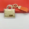 Capa exterior con marca famosa dorada, colgante de llavero de alta gama transfronterizo, regalo para la industria de la belleza, regalo para impulsar el tráfico en transmisiones en vivo, recuerdo para clientes