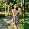 Maiô de peça única de alta qualidade, com estampa floral vintage e efeito de lavagem com tinta, apresentando um delicado decote halter e um design de saia assimétrico para uma silhueta favorecedora.