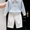 Ropa infantil coreana 2026 otoño e invierno nuevo suéter de punto de manga larga a rayas azules con cuello polo y pantalones rectos casuales para niños