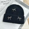 Otoño e invierno nuevo estilo viento fragante pequeño gorro de lana con lazo de bola de acero Joker para mujer circunferencia de cabeza grande protección para las orejas gorro tejido para el frío venta al por mayor