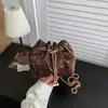 Bolsa con cordón 2026: La popular bolsa nueva para mujer de este año presenta un diseño único con una cadena, y es un bolso cruzado tipo cubo plisado para otoño.
