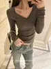 Camiseta de mujer con cuello en V, costura central, manga larga, tela suave y elástica, corte corto, ajuste ceñido, diseño simple, estilo coreano y un look elegante y atmosférico.