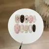 Um par de pontas de unha estilo coreano de menina doce com design de pudim de leite de amora, bolinhas, cores contrastantes, um laço e efeito olho de gato, feito à mão