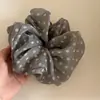 Goma para el pelo de lunares gris lechoso, fresca y versátil, con un toque de alta gama, adecuada para coletas bajas en la nuca.