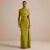 Elegante vestido de noite, vestido longo com gola alta, manga única e um grande decote nas costas, apresentando adornos de botões dourados, um recorte na cintura e tecido fluido e drapeado.