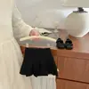 Falda corta plisada de estilo universitario para niñas en verano, elegante, de color liso, cintura elástica, versátil, anti-exposición, media falda, ropa para niños