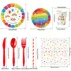Decoraciones para fiesta de cumpleaños infantil con temática de arcoíris, que incluyen platos de papel desechables, pancartas, banderines y artículos decorativos