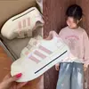 Tenis blancos para niña, nuevo estilo 2026, con diseño de Hello Kitty, cierre de velcro, estampado de huella de pata de gato, suela suave, material transpirable, puntera en forma de concha, franjas rosas y un diseño versátil