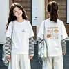 Camiseta de manga longa para meninas para primavera e outono, novo estilo 2026, peça básica moderna para crianças mais velhas, algodão puro, gola redonda, top falso de duas peças