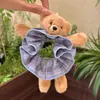 O scrunchie infantil fofo de urso com estampa xadrez azul é extremamente estiloso para prender o cabelo em um coque, proporcionando um visual sofisticado.
