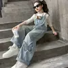 Pantalones de tirantes con parche de pajarita elegantes para niñas, nueva moda primavera 2026, jeans versátiles de estilo coreano de moda para niños mayores