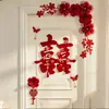 Nueva decoración de habitación de bodas estilo chino, con caracteres auspiciosos, decoraciones festivas para puertas, borlas y arreglos florales, creando un telón de fondo pintoresco para las fotos de boda.