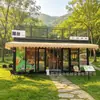 Cafetería tipo contenedor de estilo industrial con muros cortina de cristal de suelo a techo y una plataforma de observación en el nivel superior, ubicada en un distrito cultural y comercial