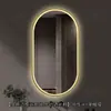 Espejo de baño inteligente ovalado en stock con lijado exterior e iluminación LED translúcida, adecuado para montaje en pared de baño y proyectos hoteleros, con opciones de personalización.