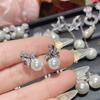 Pendientes de perlas con lazo elegantes de estilo nuevo, ligeros y de alta gama, con cuentas de aguja de plata, al por mayor.