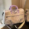 Bolsa de mano bordada con bloques de color y un delicado detalle de lazo, perfecta para viajar, ofreciendo amplio espacio para viajes cortos.