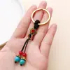 Llavero de cuerda trenzada hecho a mano estilo étnico con cuentas de turquesa roja y azul y borlas, accesorio colgante DIY producto semiacabado al por mayor