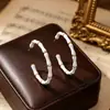 Aretes de aro negros con patrón de cruz estilo court vintage, aretes empalmados estilo mediados de siglo, lujo ligero con un toque de alta gama, aretes elegantes para mujer