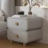 Mesita de noche de color crema con acolchado suave, esquinas redondeadas, doble cajón y patas de madera maciza, un mueble de almacenamiento simple y práctico para el dormitorio