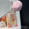 Venta al por mayor del fabricante Cadena colgante simple de perlas Bola de pelo de cristal Lanyard para teléfono móvil Cadena corta de moda Colgante Llavero