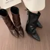 Botas femininas pretas de bico fino, salto grosso e perna larga, com um estiloso design de fivela de cinto, estilo montaria de cano alto, e comprimento que não chega ao joelho, em estilo cowboy ocidental