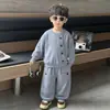 Conjunto casual simple estilo coreano para primavera y otoño para niños, que consta de una camisa de manga larga de color liso con botones y pantalones tipo jogger holgados.