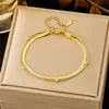 Pulseira feminina de aço titânio, lisa e elegante, com design moderno e sofisticado, em tom dourado, com trevo de quatro folhas e padrão cruzado.