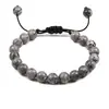 Este elegante brazalete presenta hermosas cuentas de piedra gris veteada con intrincados detalles. El diseño ajustable garantiza un ajuste perfecto para todos los tamaños de muñeca, mientras que los patrones de piedra natural lo convierten en un accesorio único para cualquier ocasión. Ideal tanto para uso casual como formal.