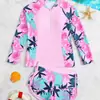 Maiô feminino de duas peças rosa com estampa floral tropical, mangas longas, zíper frontal parcial, mangas raglan e shorts combinando para proteção solar