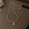 Collar de cuentas de mijo con colgante ovalado dorado para mujer, cadena para la clavícula de lujo ligero vintage de nicho, accesorio elegante y versátil