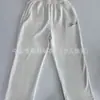 Calça moletom casual off-white com cintura elástica, corte reto de perna larga, bordado inglês na frente e nas costas, calça de malha com múltiplos bolsos