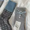 ¡Tan coreano! Es difícil resistirse a estos calcetines gris azulados con dulces lazos de cinta y botones, perfectos para otoño e invierno.