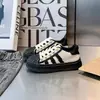 Zapatillas para niños 2026 primavera-verano nuevo estilo puntera de concha antideslizantes casuales para niñas con cordones a la moda versátiles negro y blanco zapatos para niños