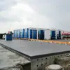 En invierno, se utiliza el dispositivo de limpieza de neumáticos de salida de agua a alta presión para vehículos modernos en la puerta del parque logístico.