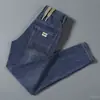 Calça jeans elástica transfronteiriça para primavera e outono para homens, corte slim estilo coreano, marca da moda, bordado simples, calça casual moderna e versátil