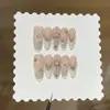 Un par de uñas postizas estilo francés hechas a mano, con diseño degradado rosa nude y crema de leche de coco, estilo ojo de gato talladas y adornadas.